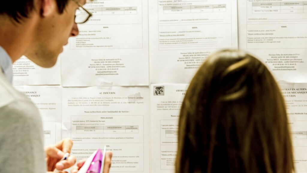 Deux personnes devant des affiches d’emploi.