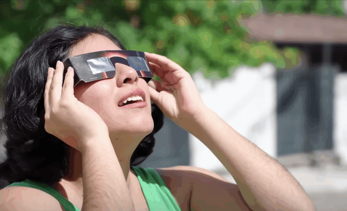 Femme qui regarde une éclipse avec des lunettes de protection